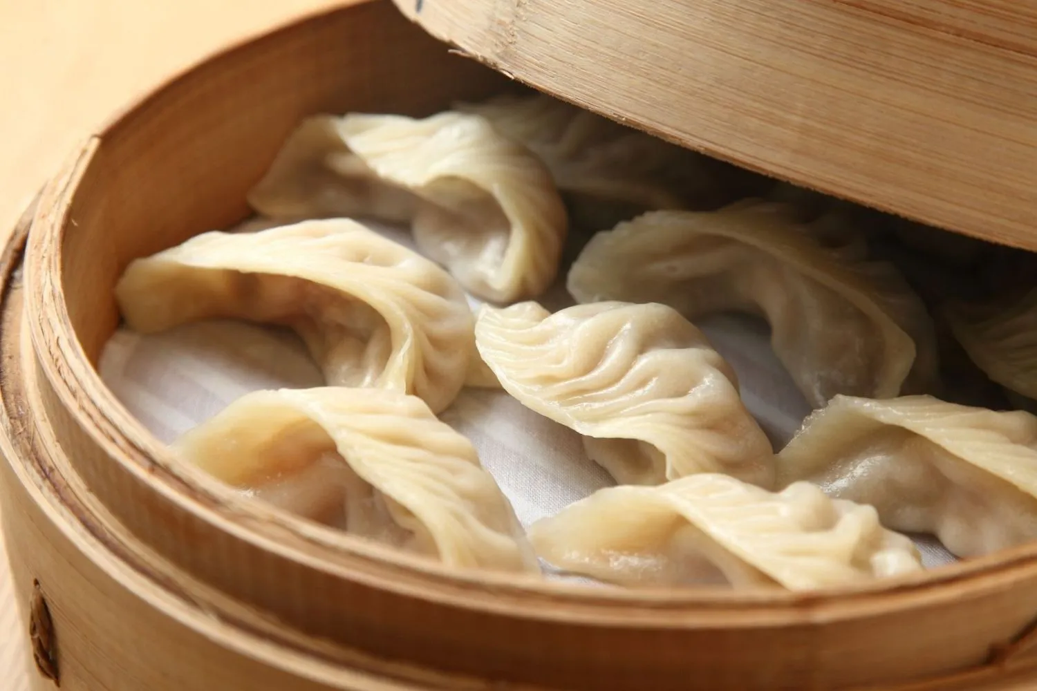 Steamed pork dumplings in a bamboo steamer basket at Fusan Dumpling House & Sushi, an Asian Fusion Restaurant in New York
